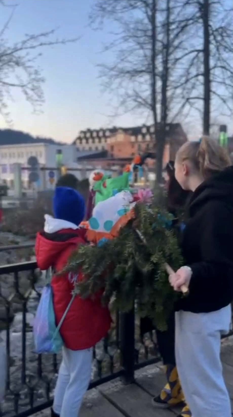 Kilka osób wrzuca Marzannę do strumyka.