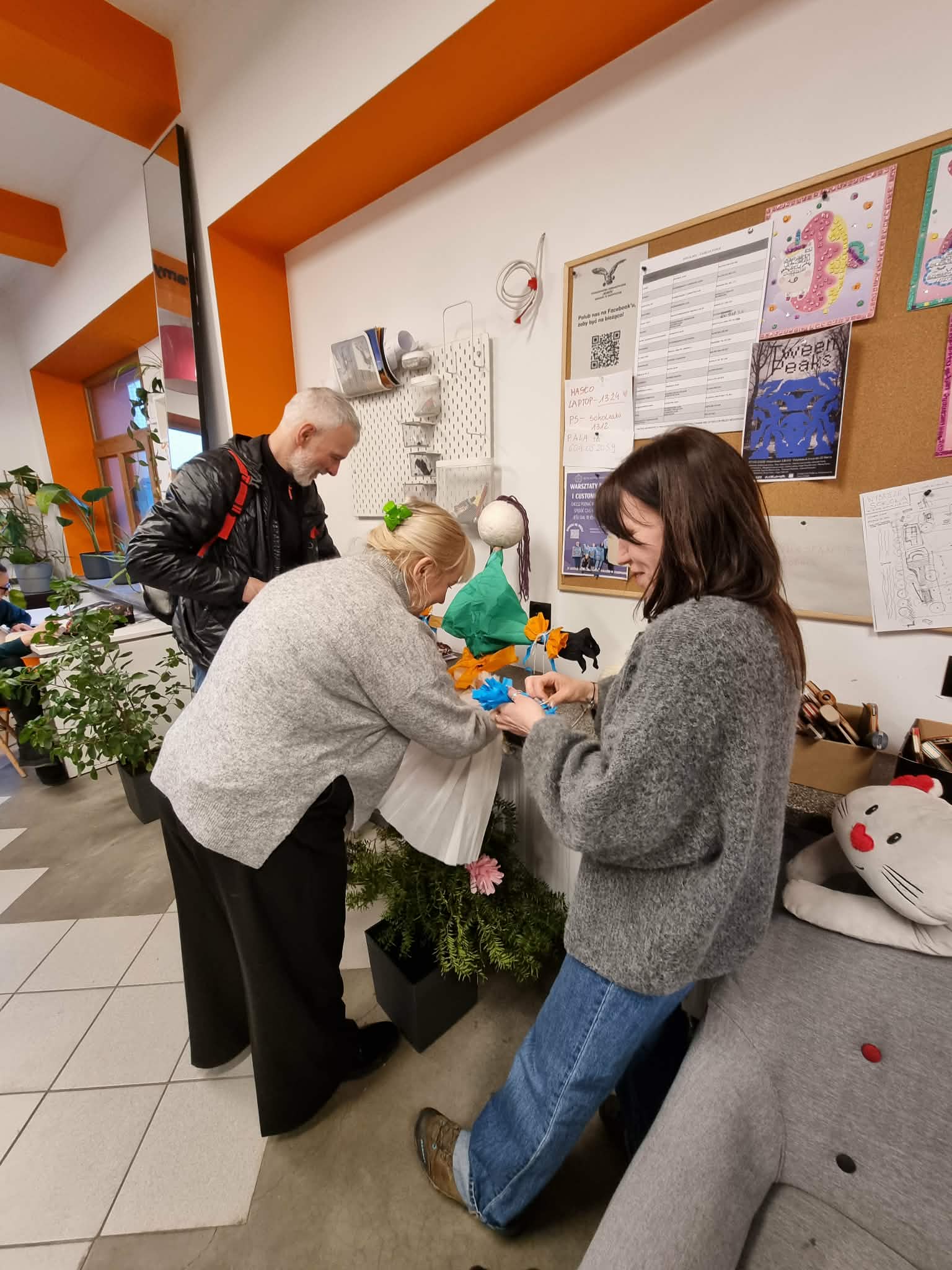 Kilka osób robi kolorowe ozdoby do Marzanny.