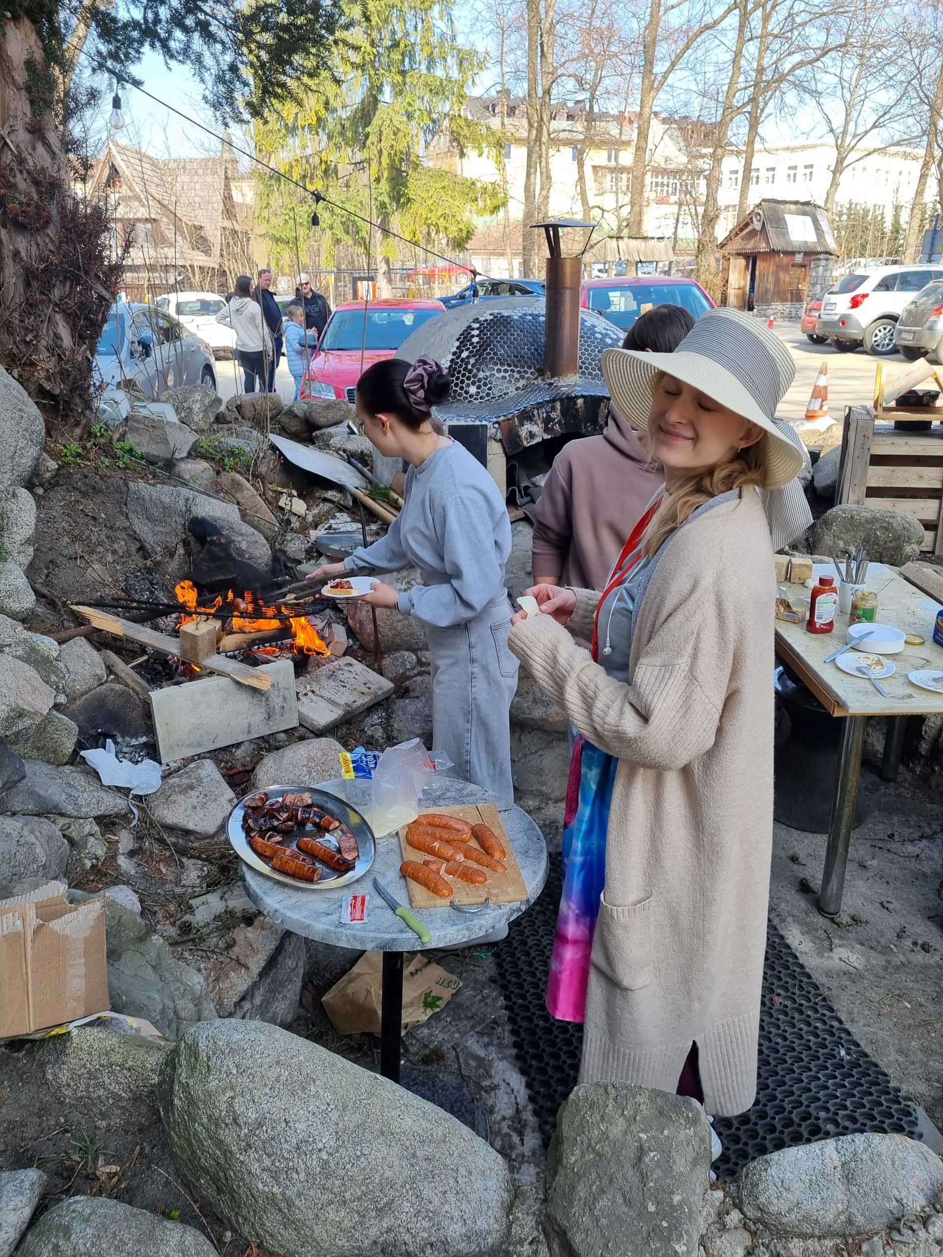kobieta w kapeluszu je pieczoną kiełbaskę
