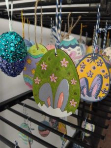 Kilka różnych pisanek powieszonych na stojaku.
