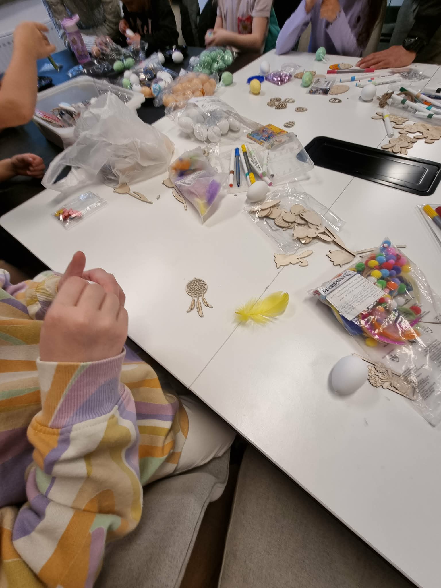 Stół na, którym znajduje się dużo różnych materiałów do ozdabiania pisanek.