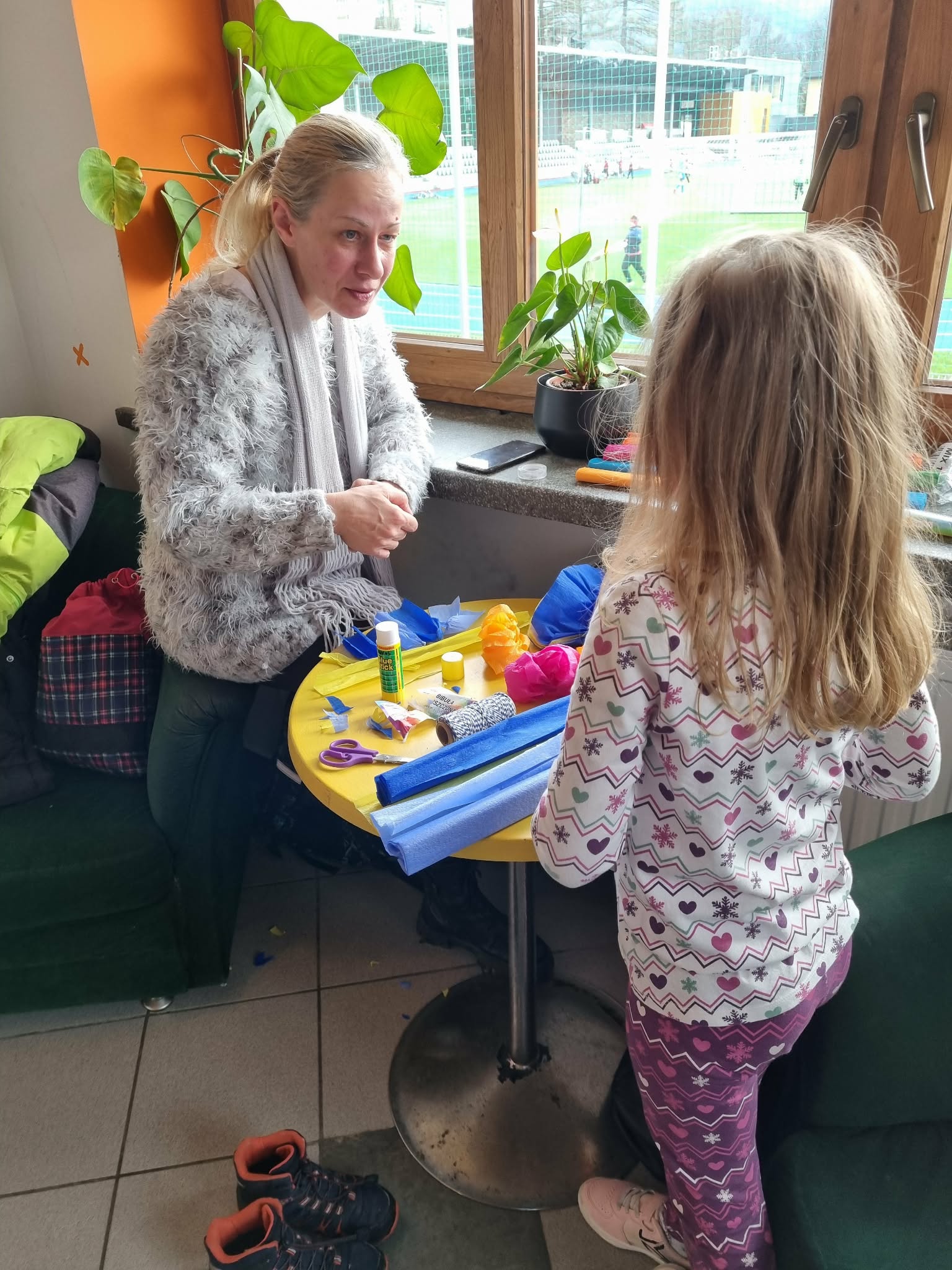 Kobieta z dziewczynką stoją obok stołu gdzie jest dużo bibuły