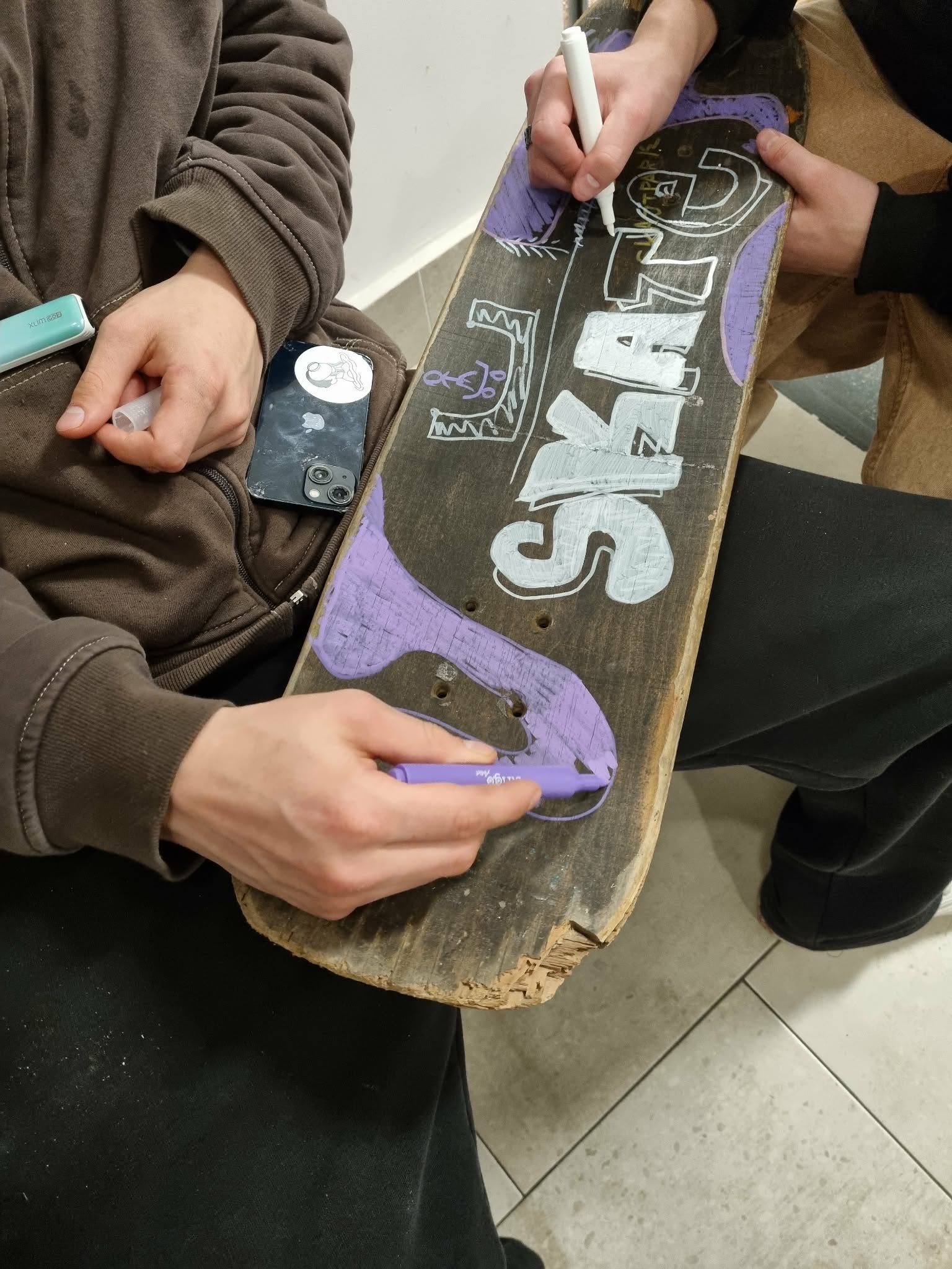 Dwóch chłopaków ozdabia starą deskorolkę