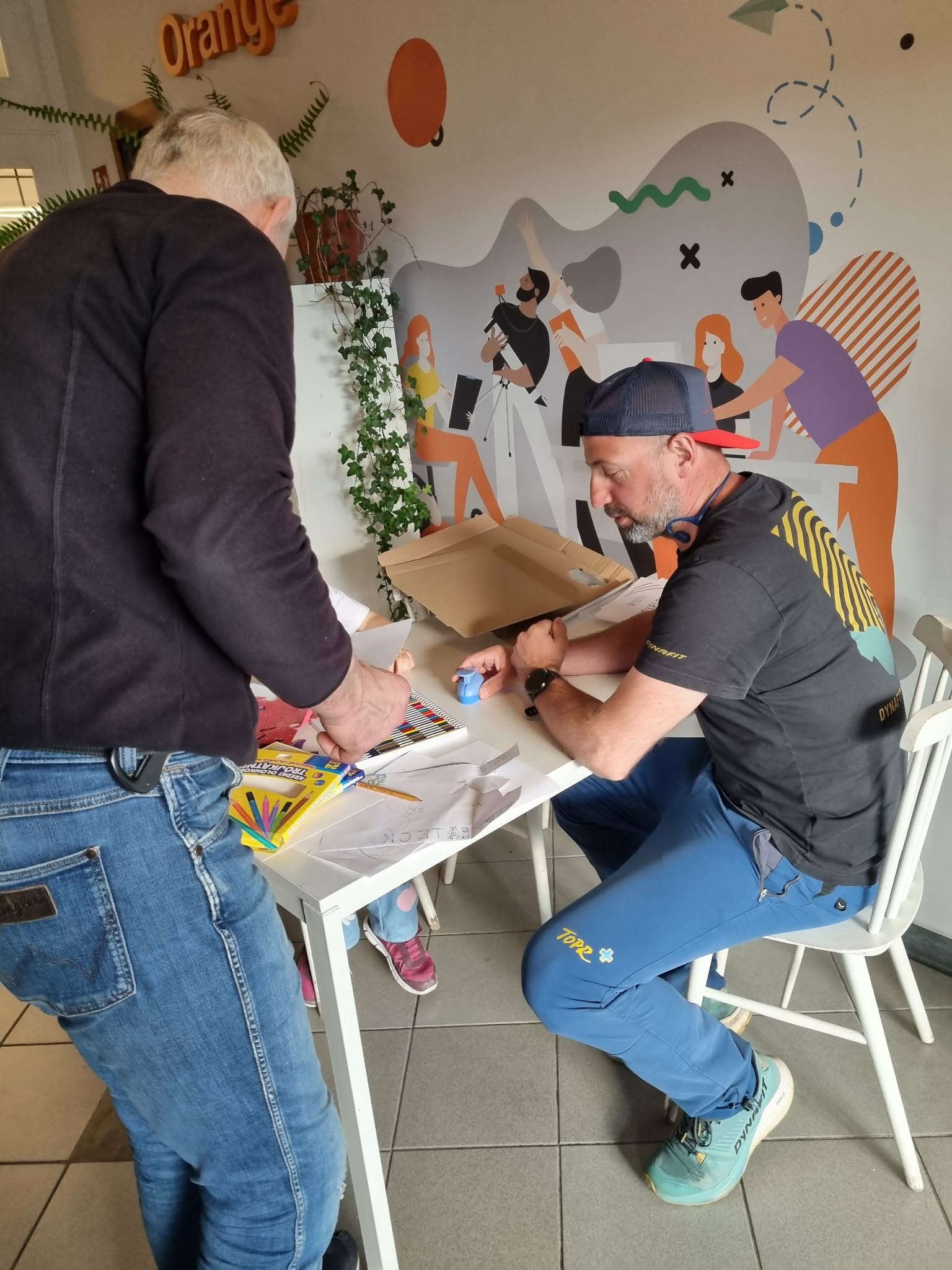 Dwóch mężczyzn siedzi przy stole i rysuje