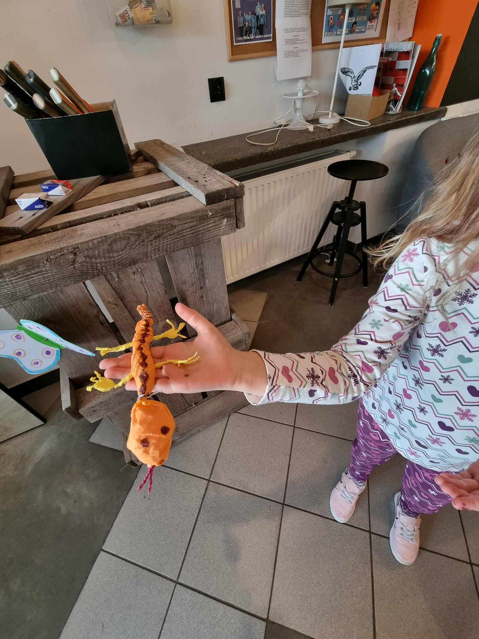 Dziewczynka trzyma pomarańczową jaszczurkę z bibuly