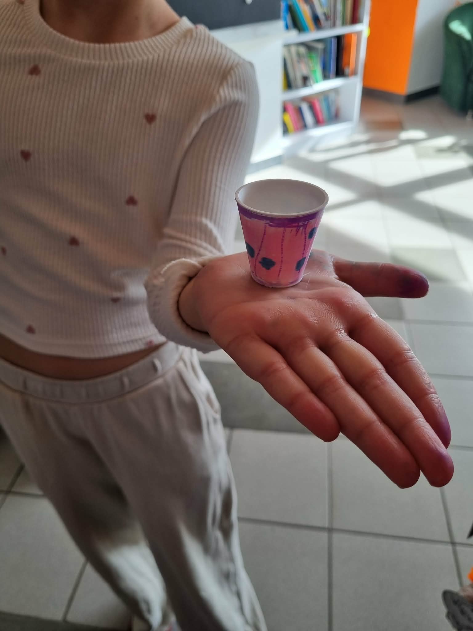 Dziewczynka ma na dłoni maleńką różową doniczkę