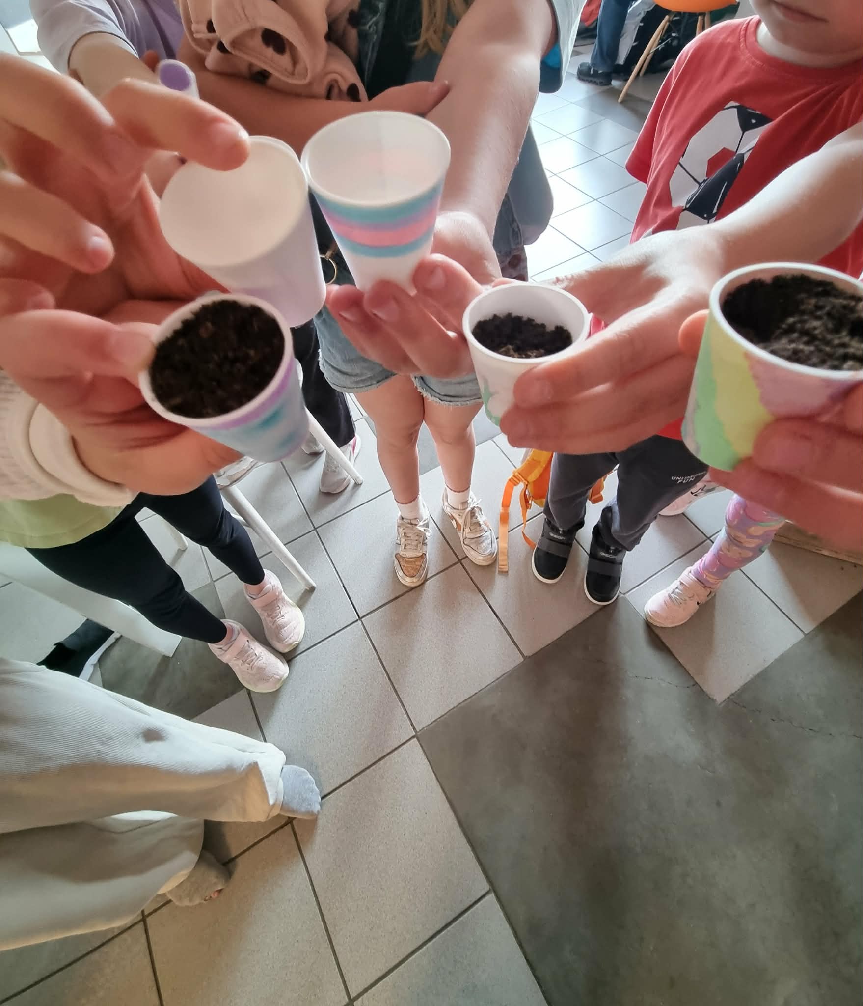 Grupa dzieci trzyma pomalowane mini doniczki