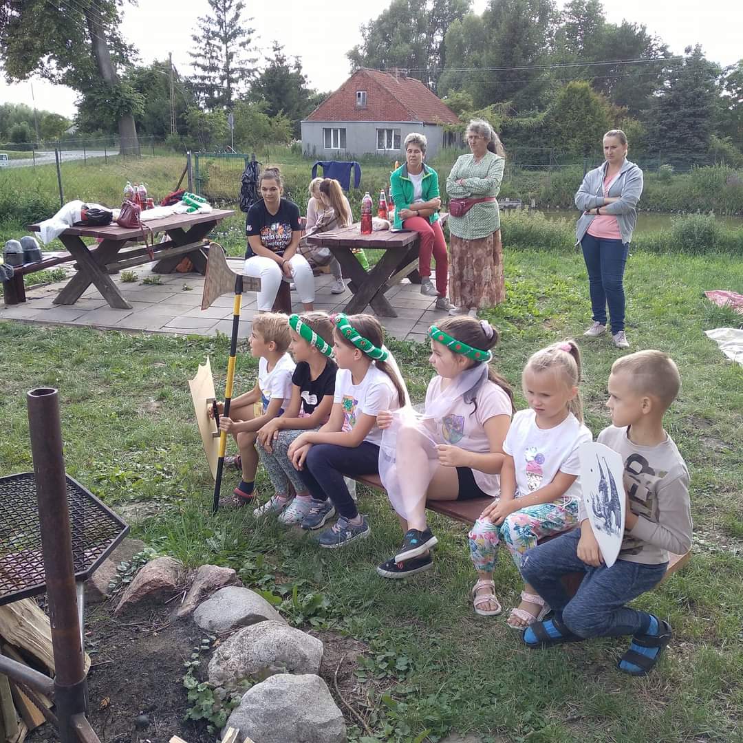 Dzieci siedzące na ławce przy miejscu na ognisko.