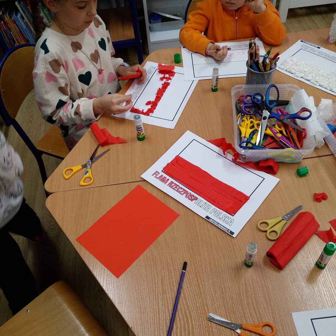 Dzieci tworzą flagę Polski z papieru.
