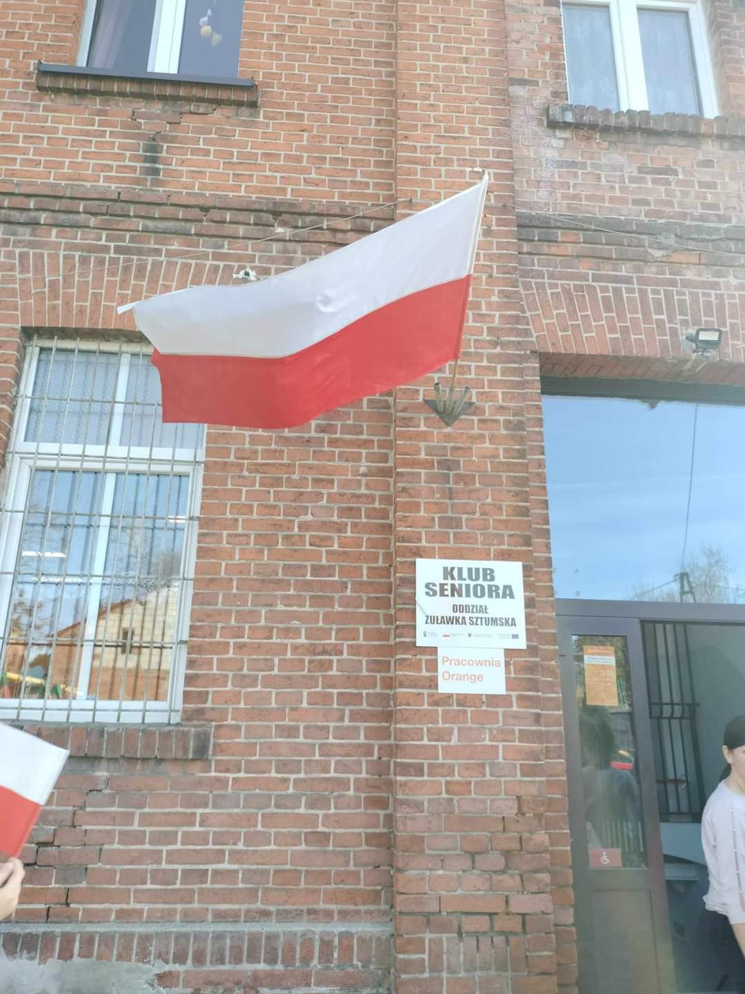 Flaga Polski wisząca na budynku.