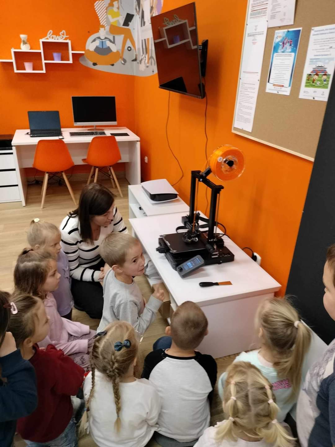 Grupa dzieci zapoznających się z drukarką 3D.