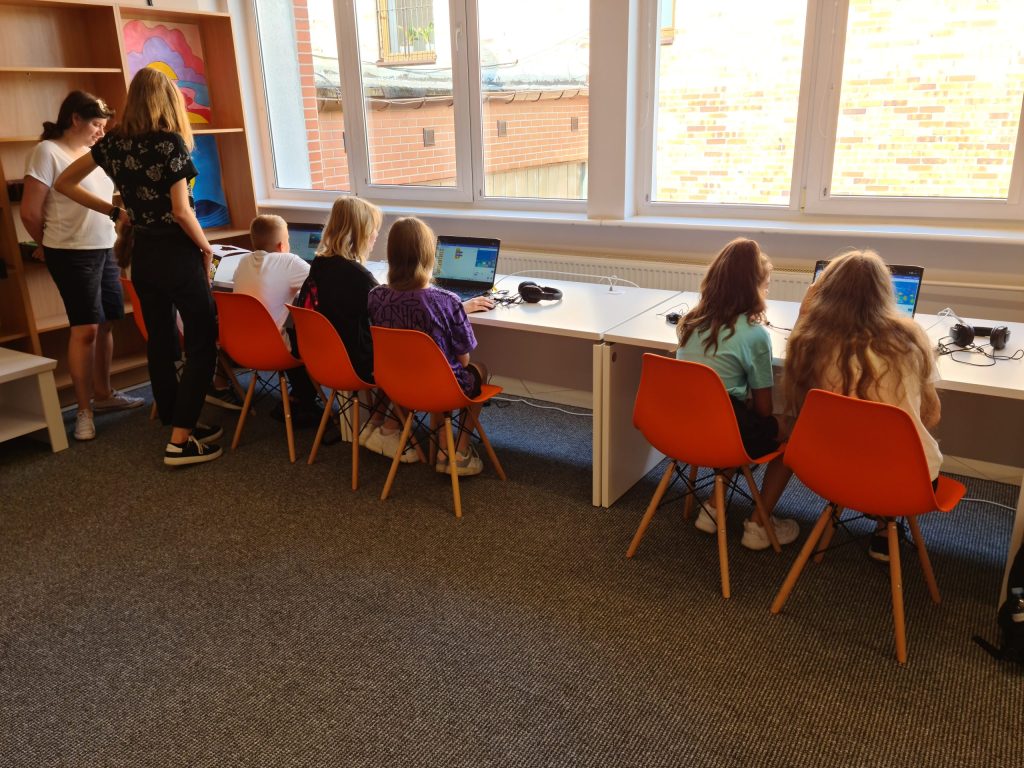 Grupa dzieci wykonuje zadanie z programowania na laptopach
