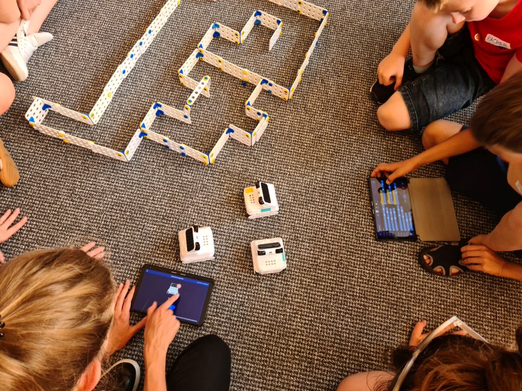 Grupa dzieci steruje robotami za pomocą tabletów