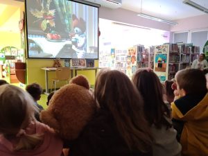 Grupa dzieci oglądających bajkę na ekranie projekcyjnym.