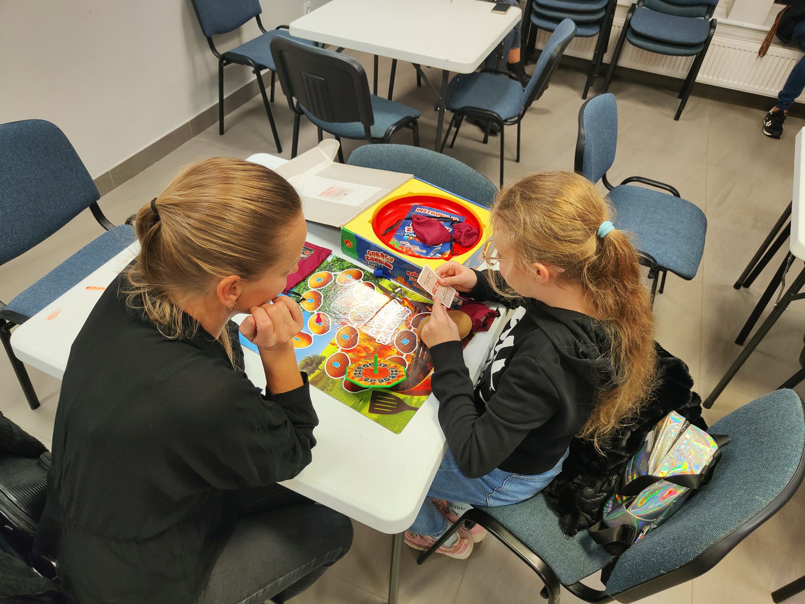 Widok z góry na dziewczynkę i kobietę grające w grę planszową przy stole.