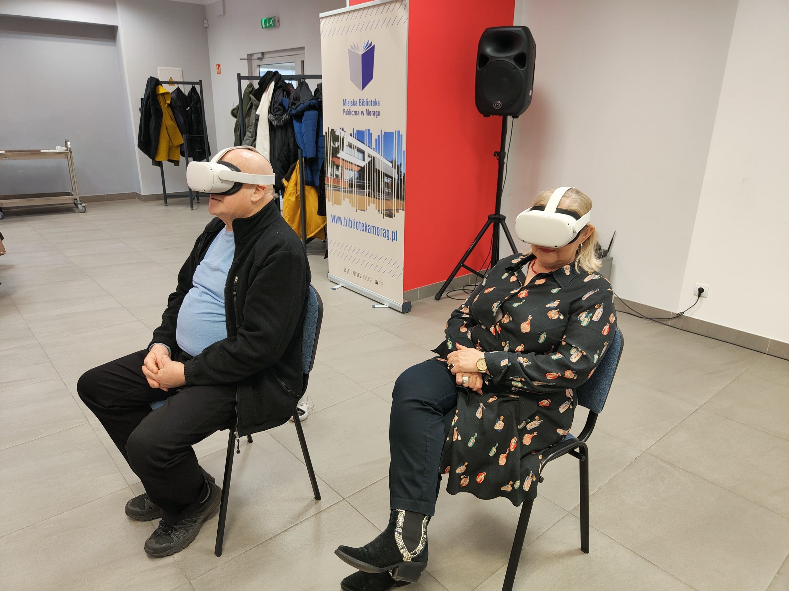 Dwie osoby siedzą na krzesłach z założonymi na głowę goglami VR.