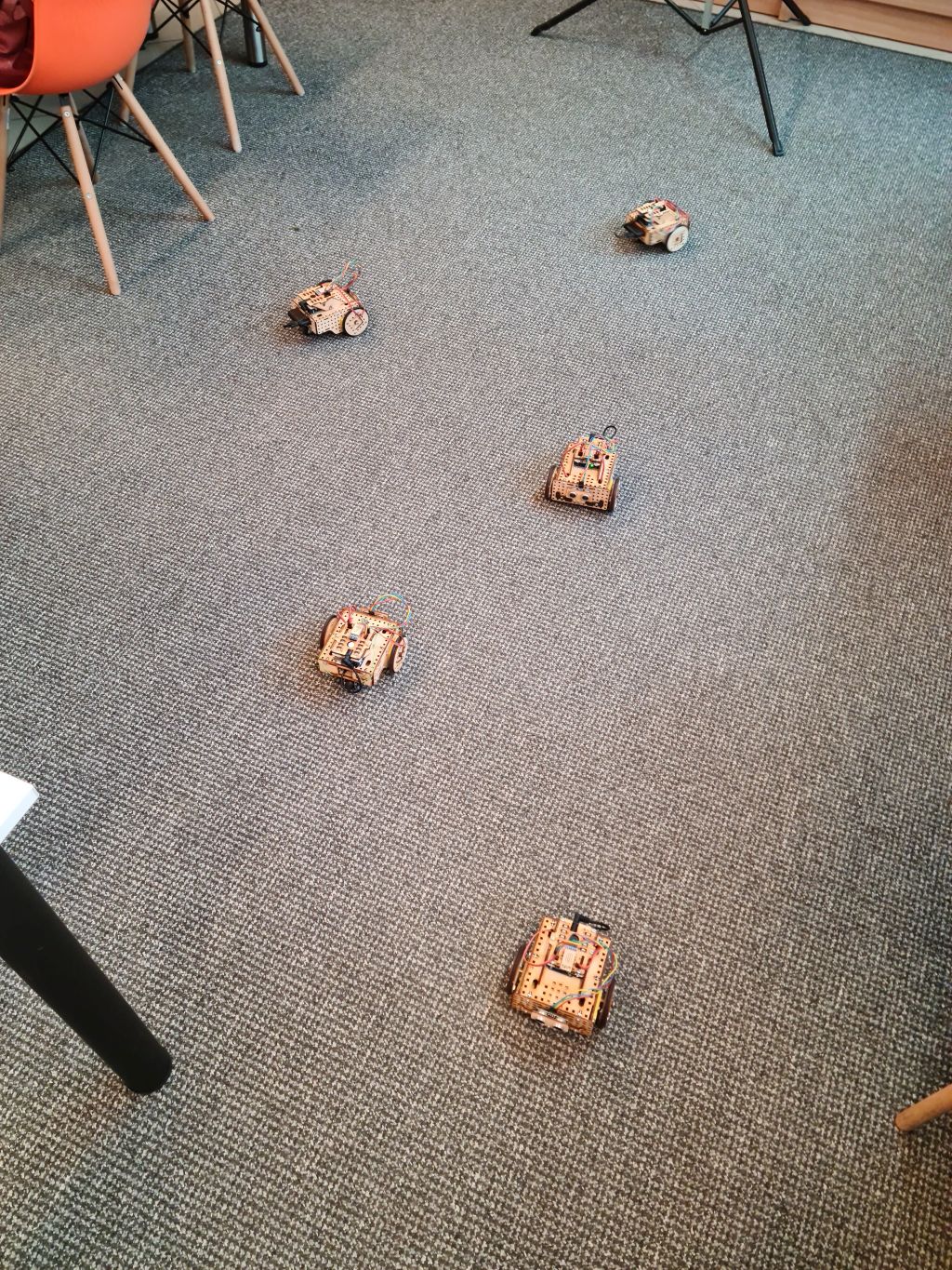 Widok z góry na pięć małych robotów ze sklejki umiejscowionych na podłodze.