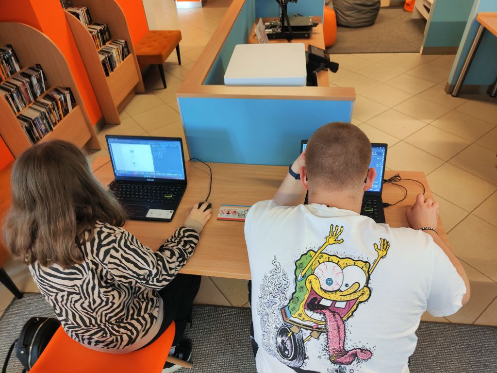 kobieta i mężczyzna siedzą przy laptopach