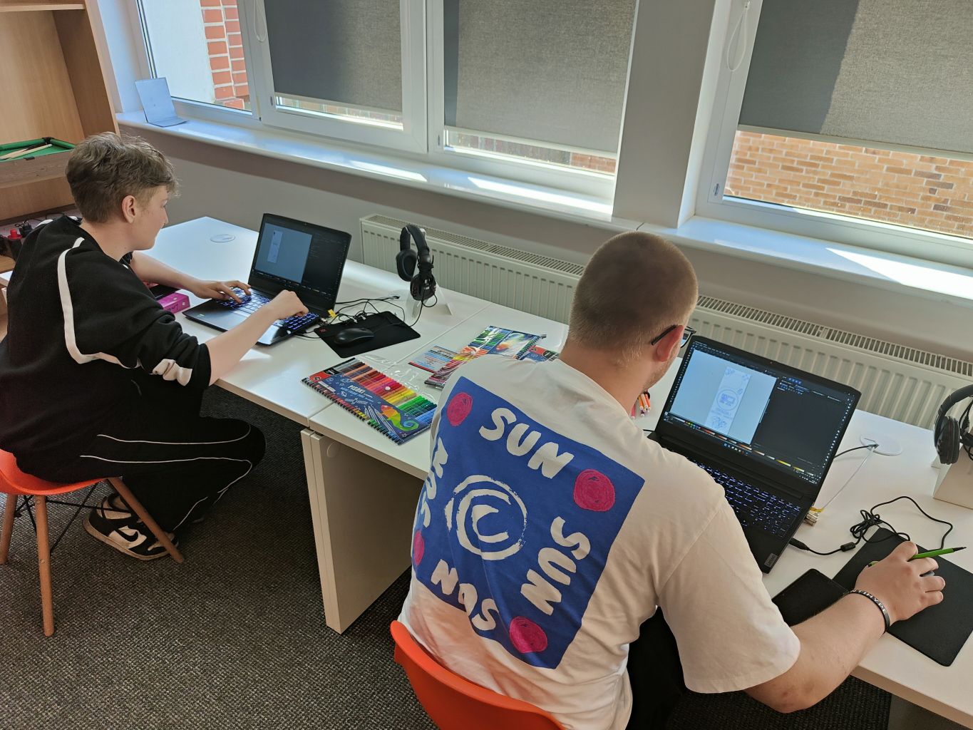 Dwóch chłopaków pracujących przy laptopach.