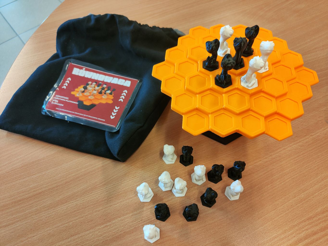 gra planszowa Równowaga - pomarańczowa platforma na podstawce, czarne i białe pionki oraz torba na wszystkie elementy