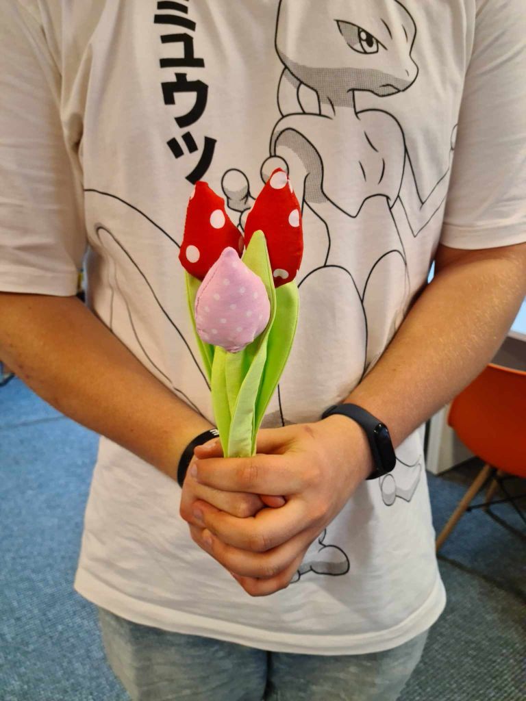 Chłopak trzyma trzy kwiaty uszyte z materiału