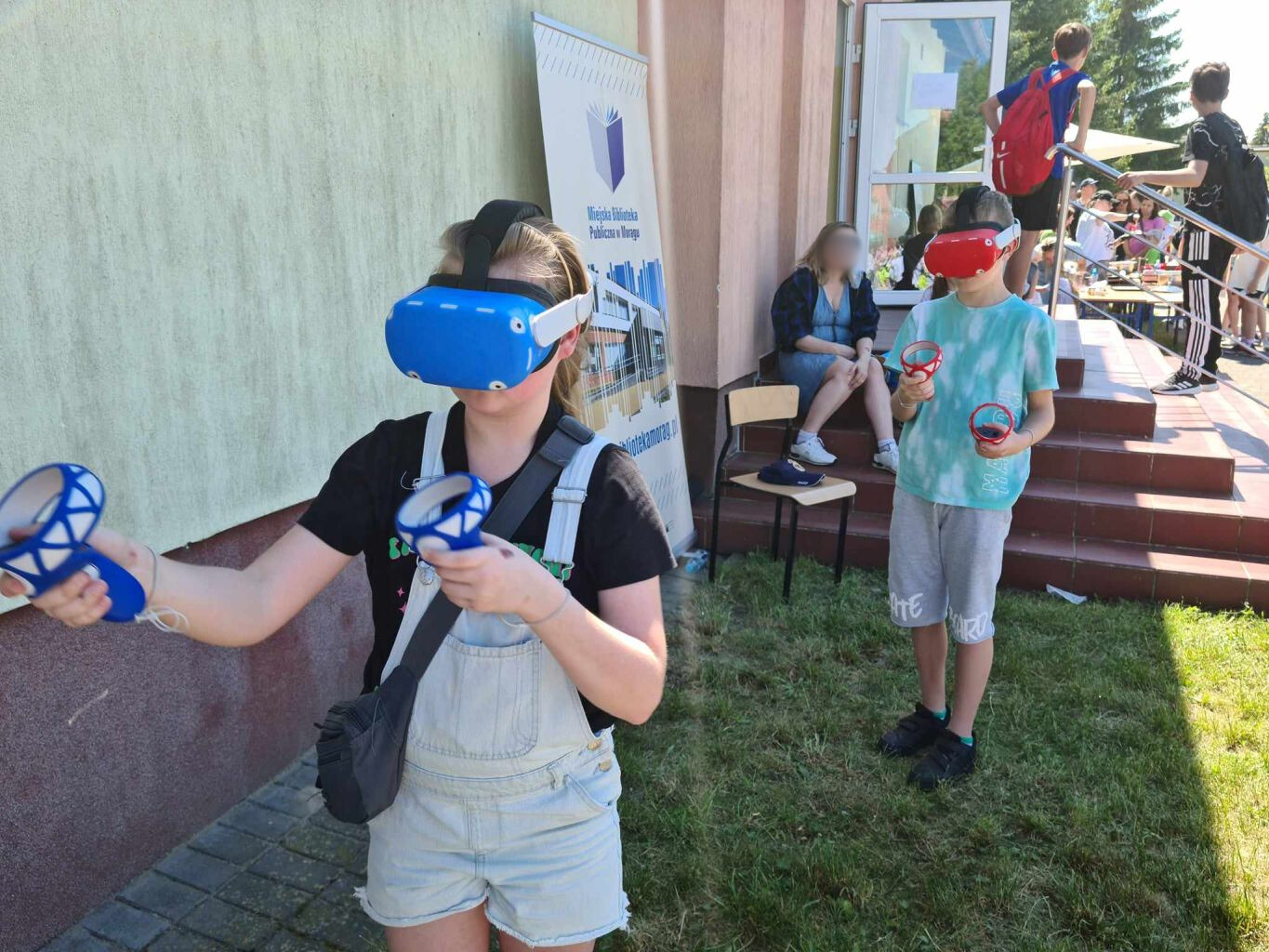 chłopiec i dziewczynka korzystający z gogli wirtualnej rzeczywistości pod budynkiem szkoły