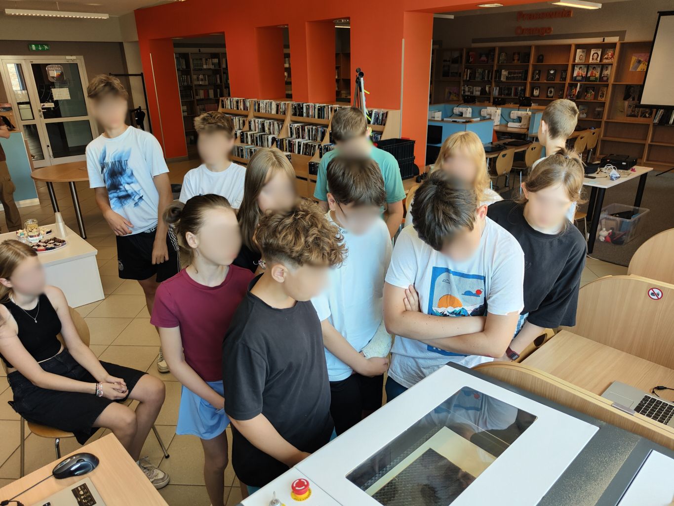 grupa nastolatków stoi wokół ploter laserowego