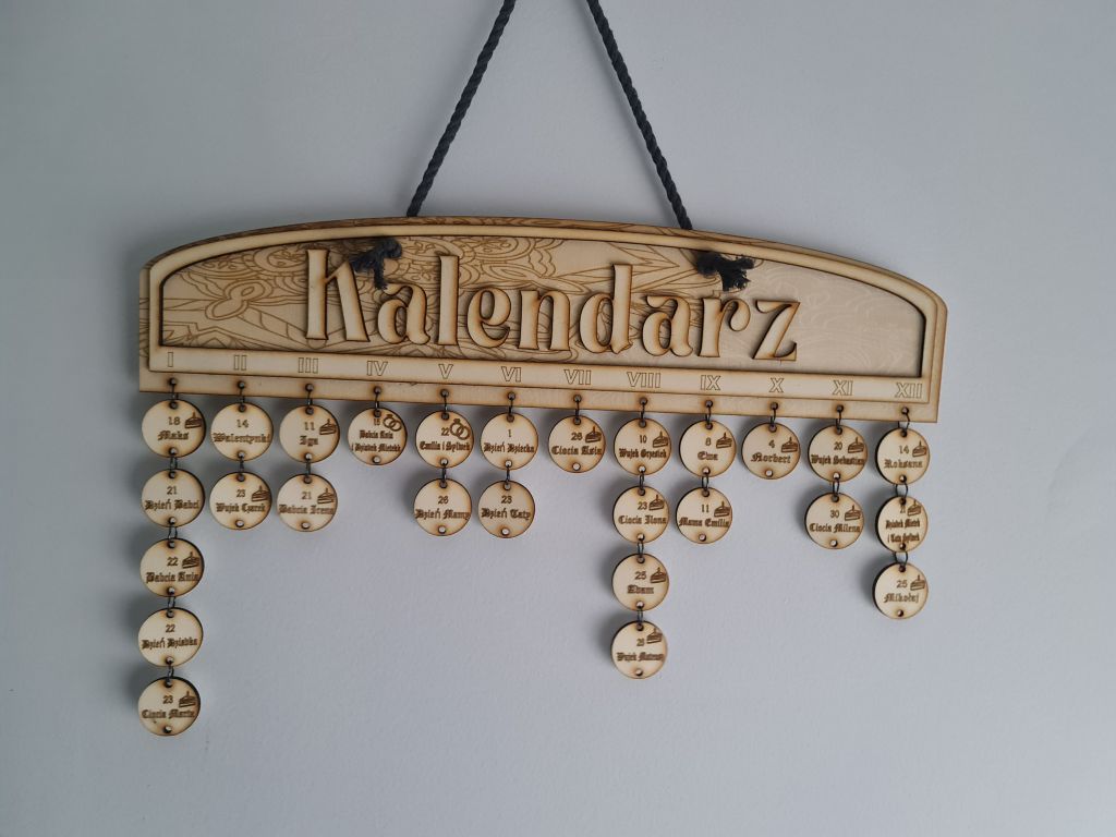 Ozdoba ścienna ze sklejki, deska z napisem kalendarz, pod nią liczne kółeczka