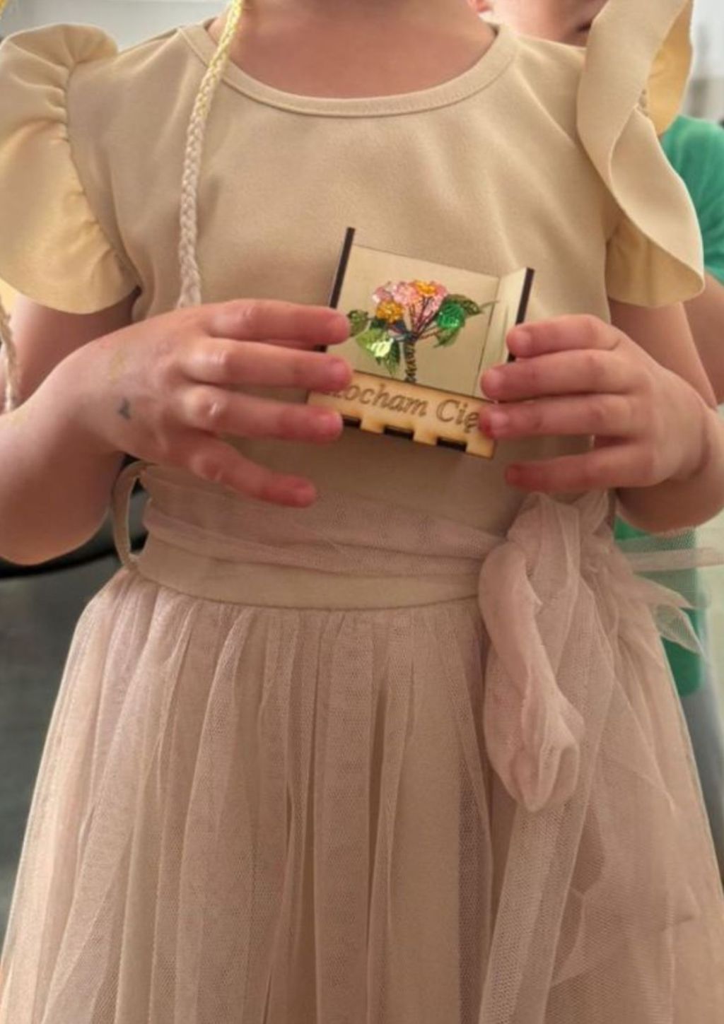 dziewczynka trzyma w ręku drewniane pudełeczko, kadr nie obejmuje głowy
