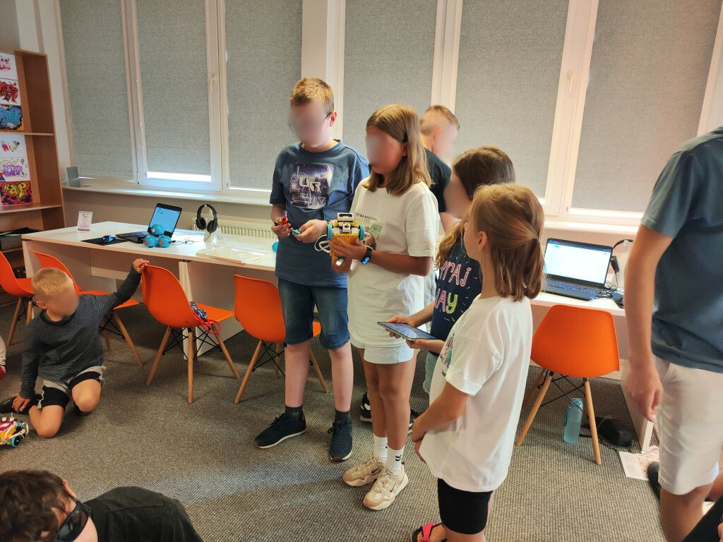 grupa dzieci stoi i prezentuje robota z klocków lego