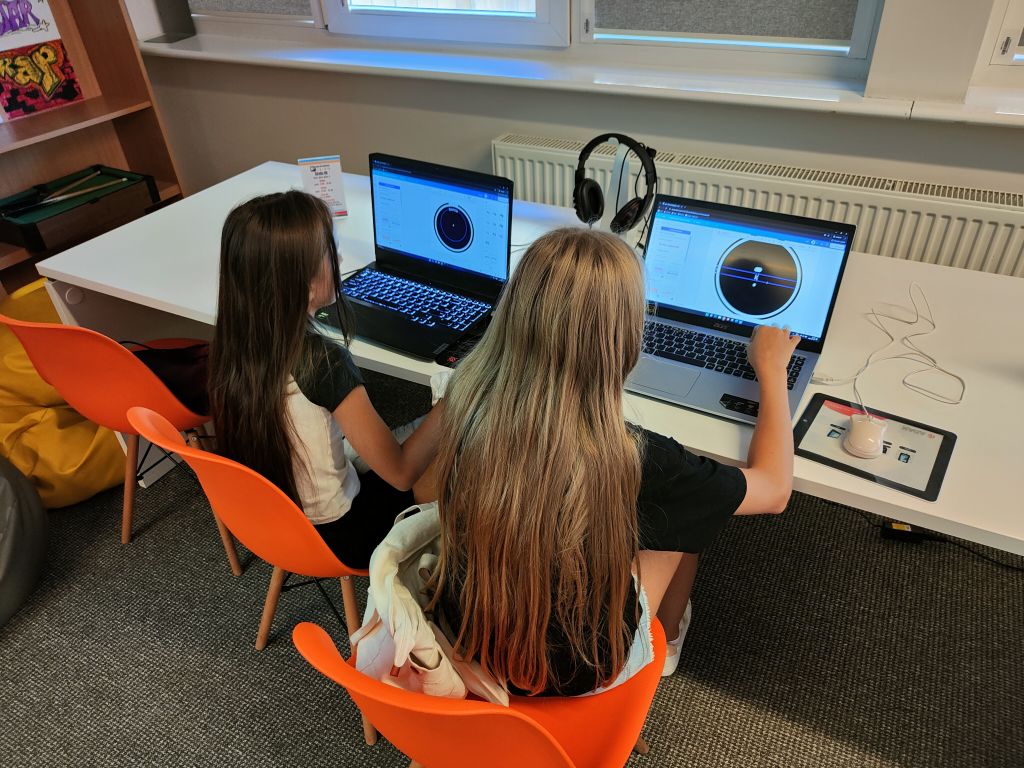 dwie dziewczynki siedzą przy laptopach