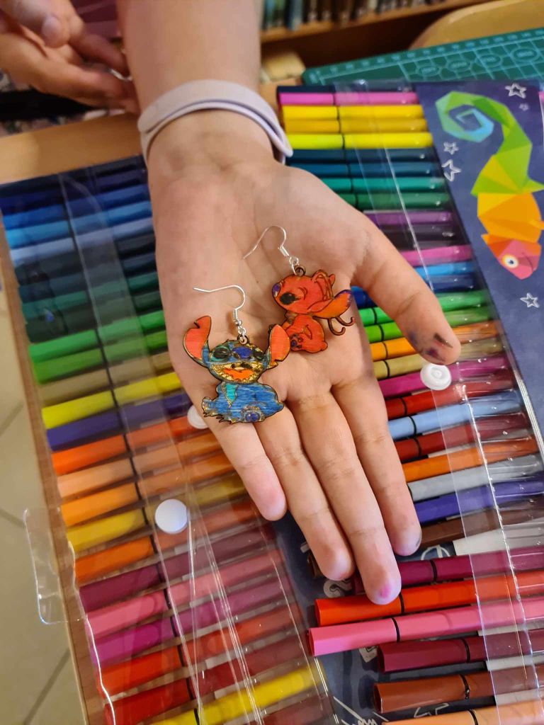 rozłożona dłoń na której leżą kolczyki ze sklejki