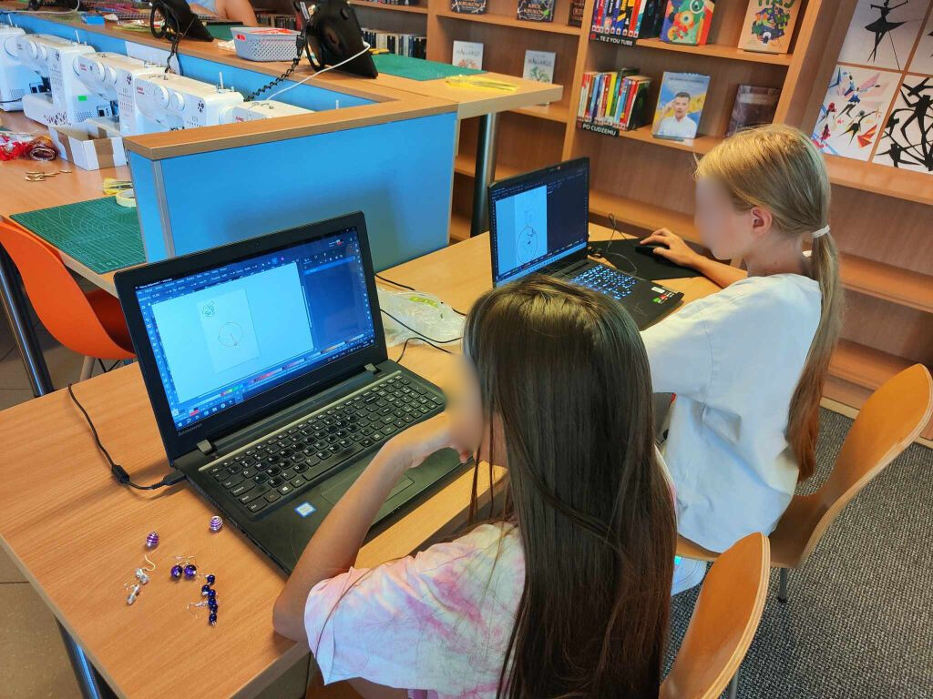 dwie dziewczynki siedzą przy laptopach