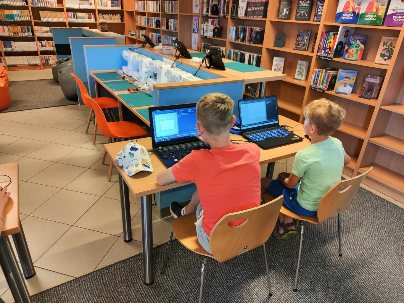 dwójka chłopców siedzi przed laptopami