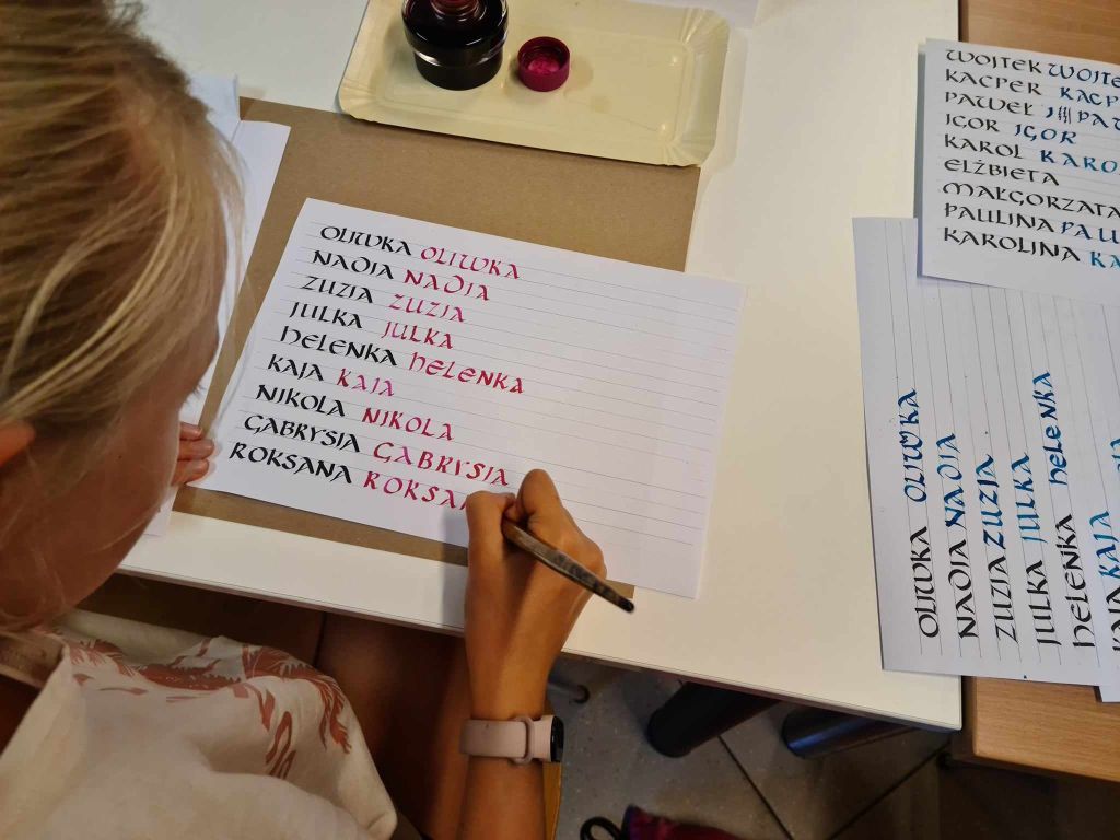 Dziewczynka ćwiczy kaligrafię na przygotowanych wzornikach z imionami