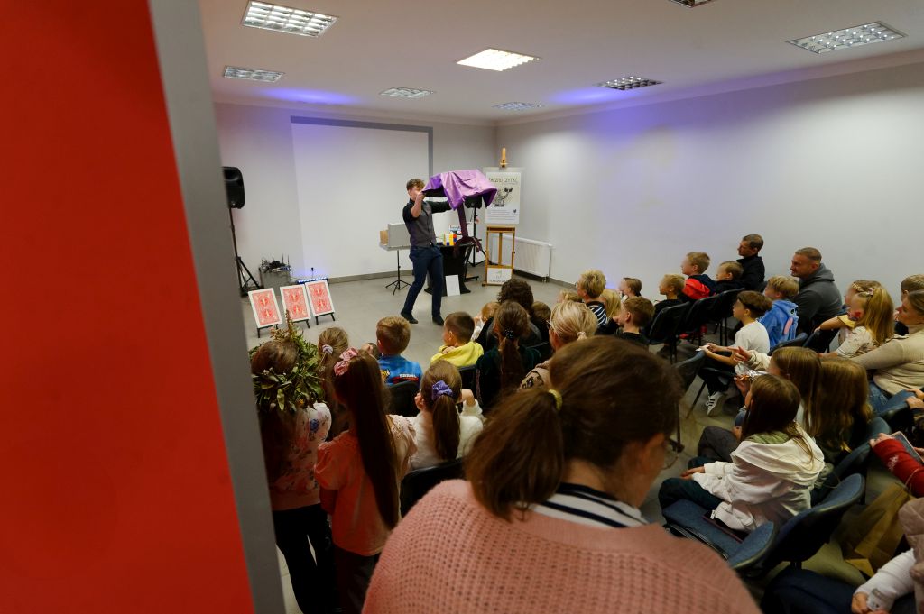 iluzjonista podnosi stolik, przed nim widownia