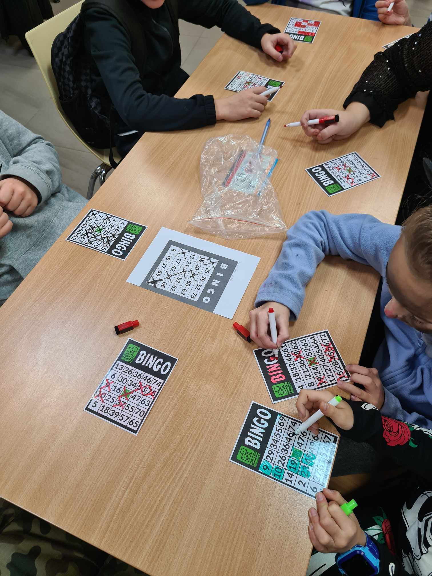 kilka osób siedzi przy stoliku u grają w bingo