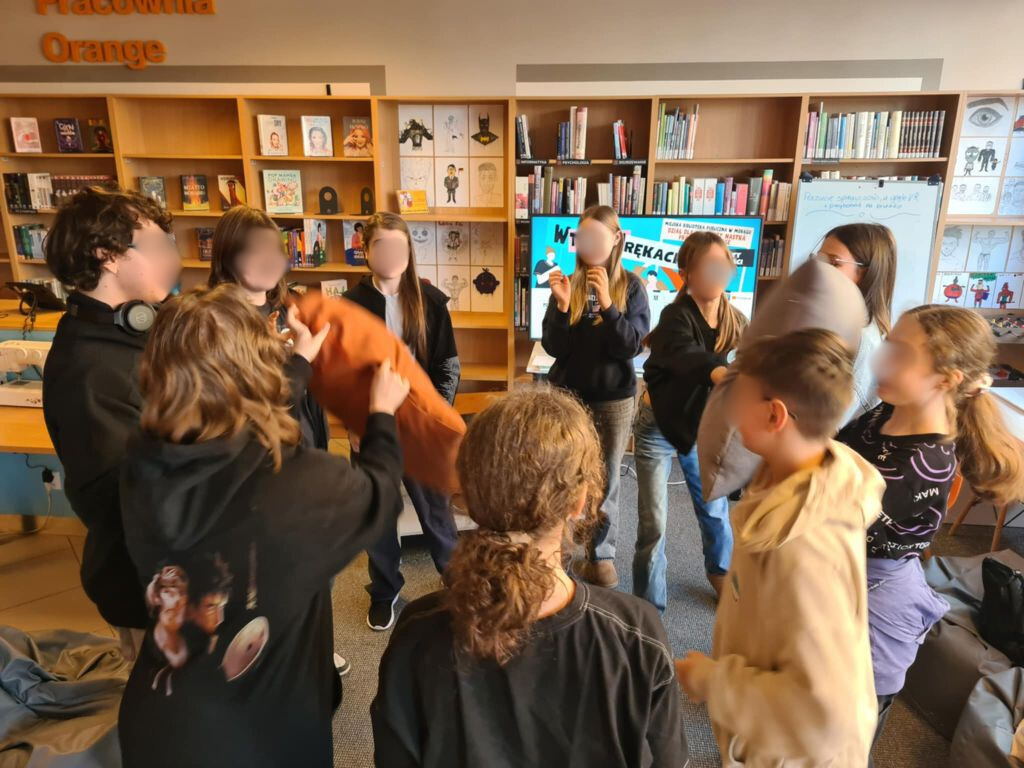 grupa nastolatków stoi w kółku i podaje sobie poduszki