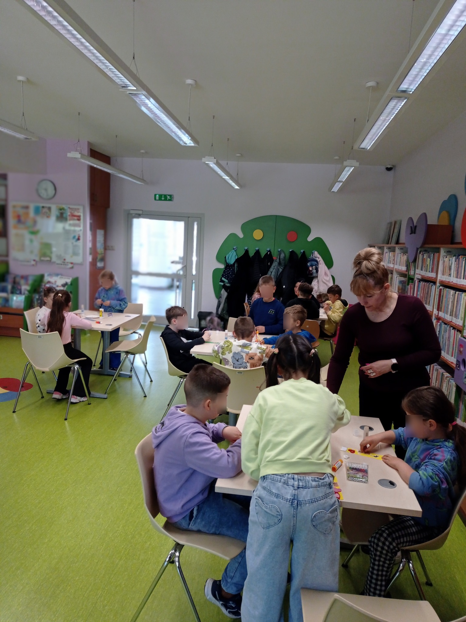 grupa dzieci siedzi przy stołach, wykonują pracę plastyczną