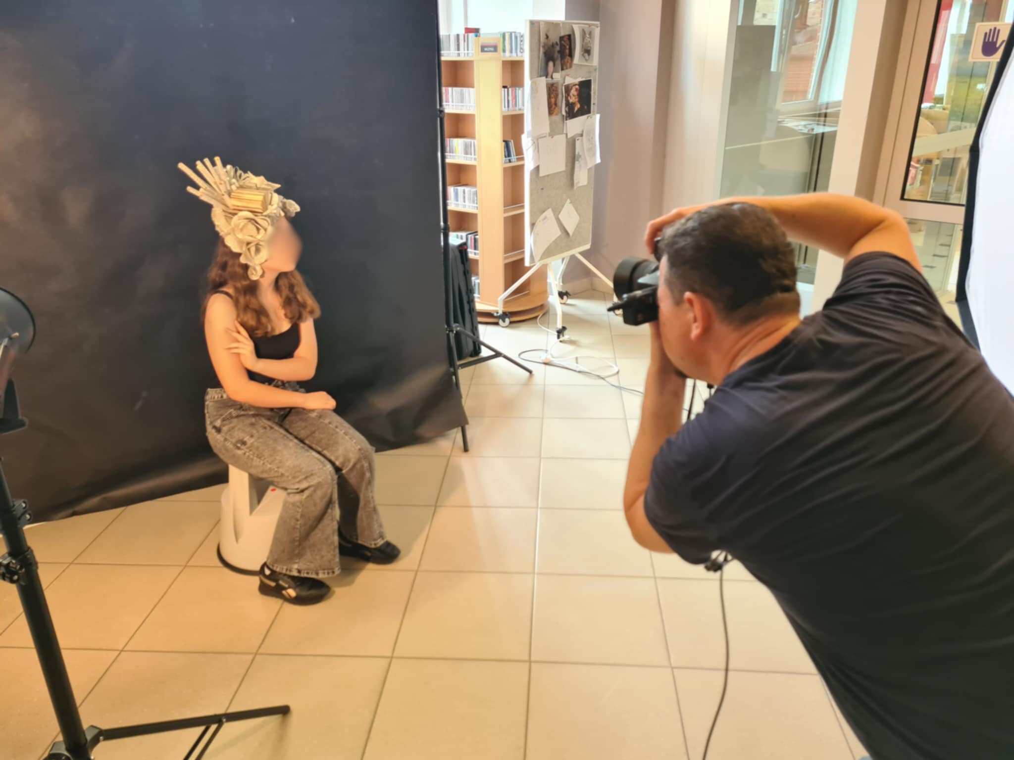 Fotograf robi zdjęcie dziewczynie w ozdobnym nakryciu głowy na tle czarnego tła.