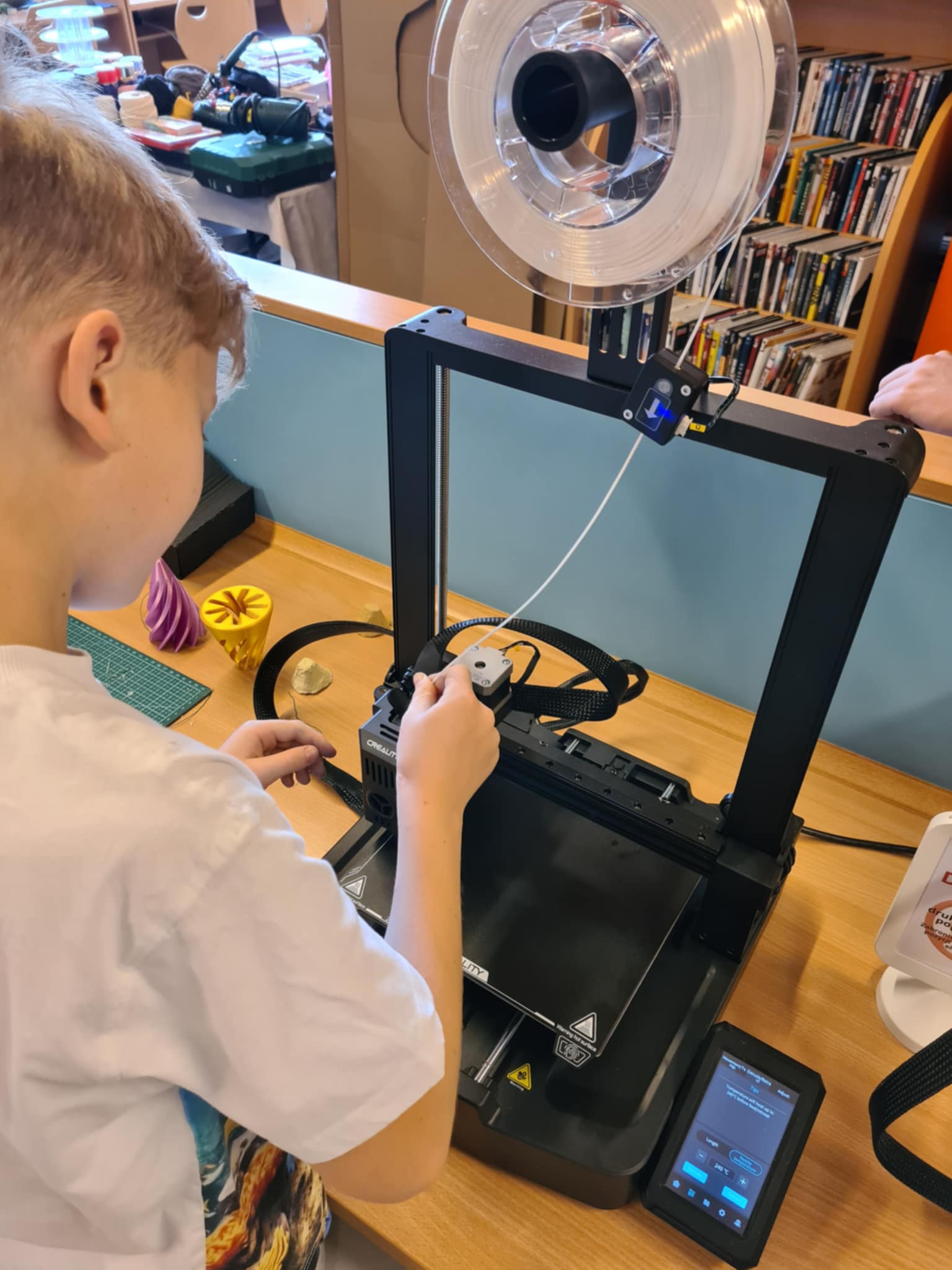 Chłopiec pracuje przy drukarce 3D.