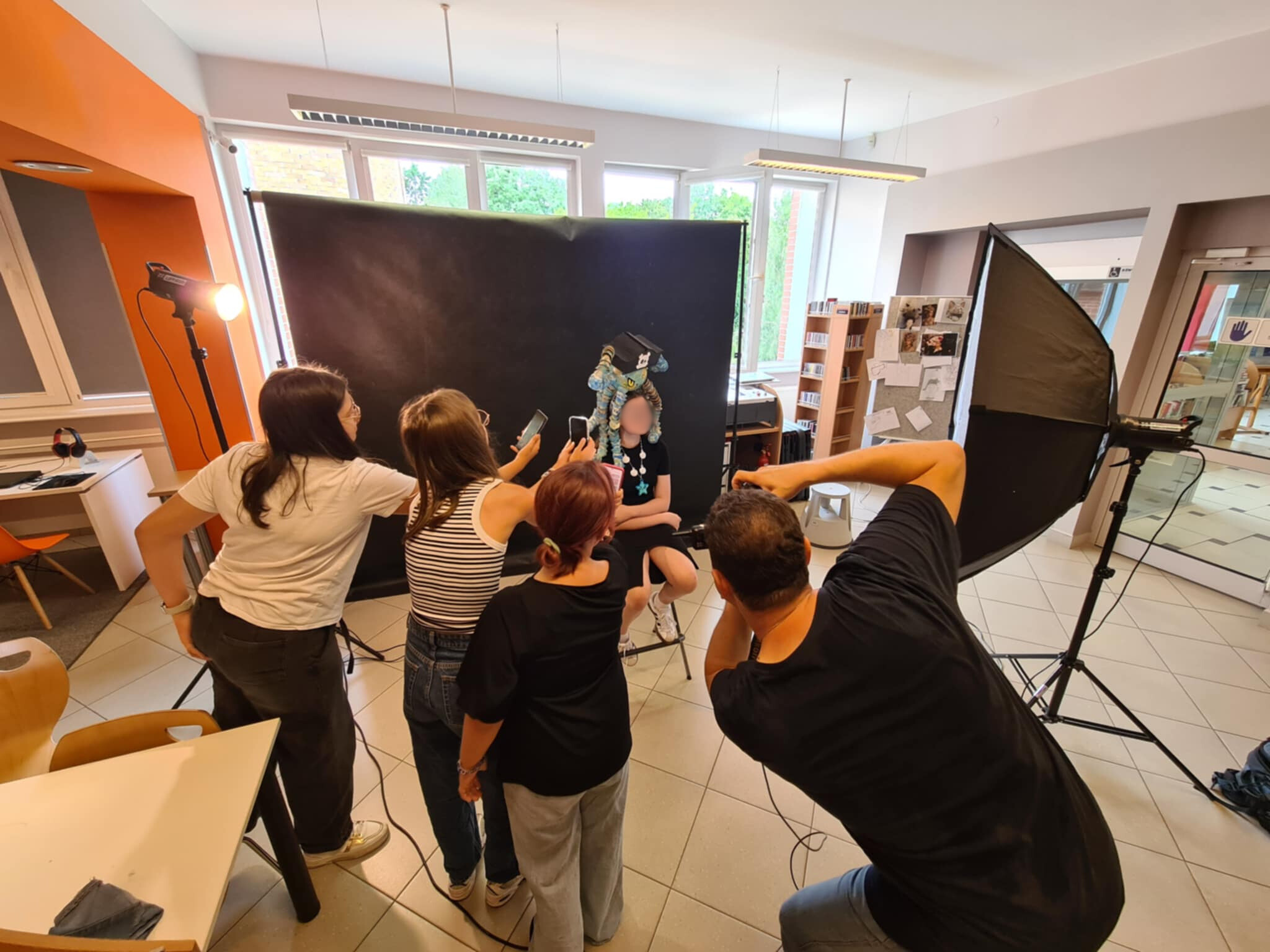 Grupa młodzieży pomaga w ustawieniu modela do zdjęcia, fotograf przygotowuje ujęcie.