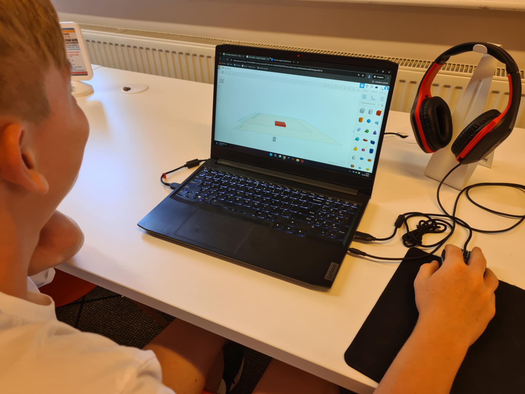Chłopiec projektuje obiekt w programie 3D na laptopie.