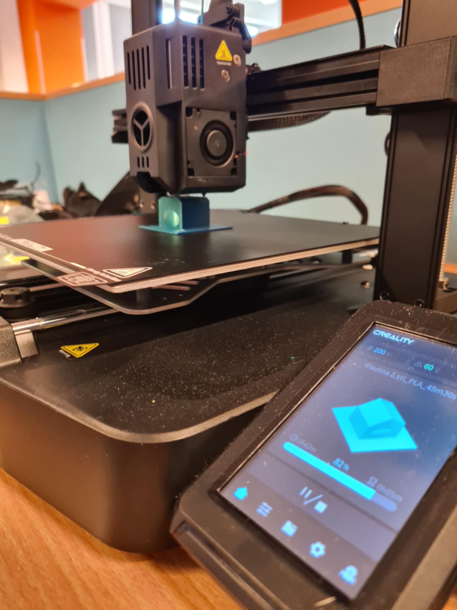 Drukarka 3D Creality w trakcie drukowania niebieskiego modelu, ekran pokazuje 82% postępu — technologia w akcji!