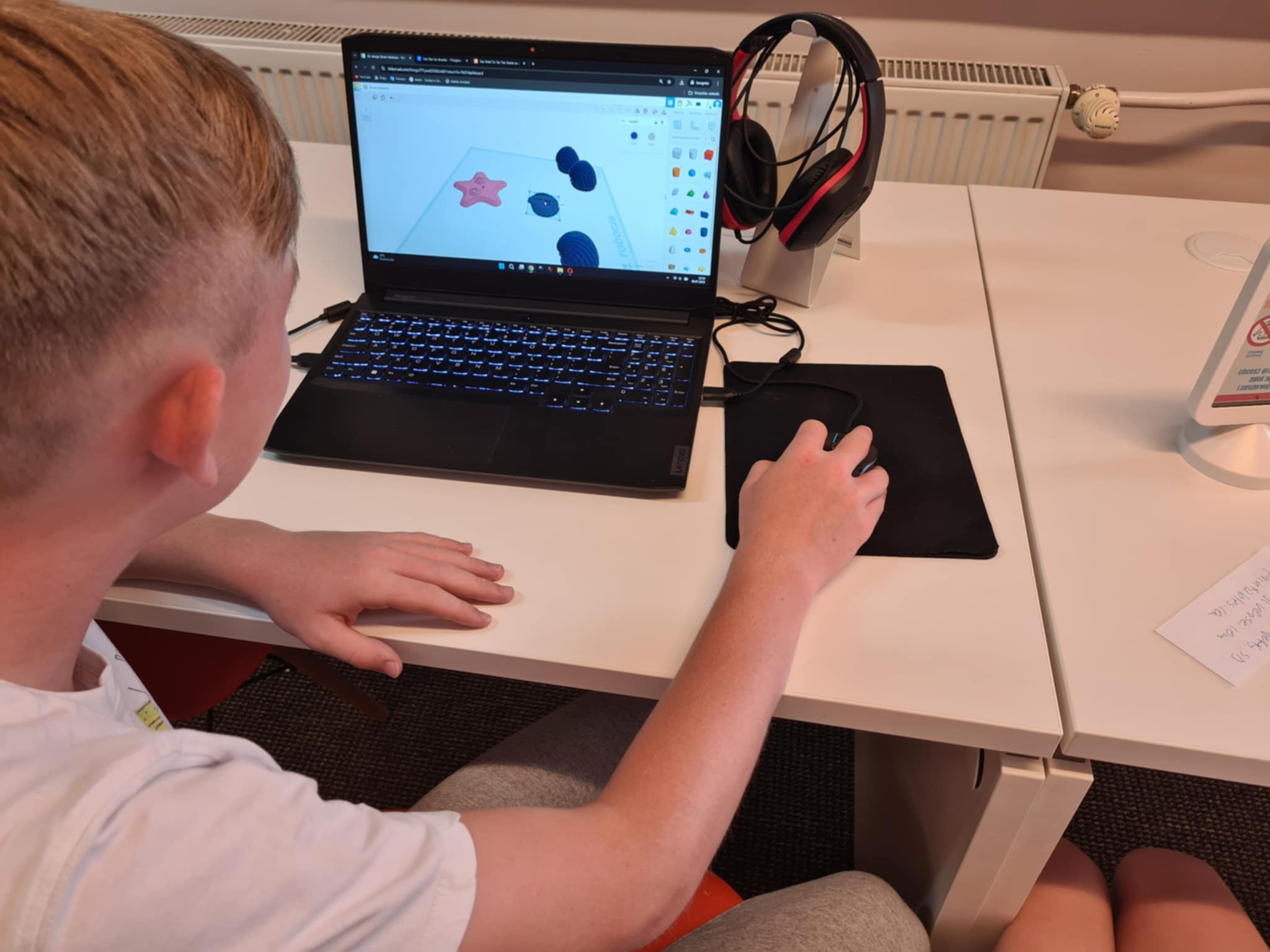 Chłopiec projektuje elementy w programie 3D na laptopie.