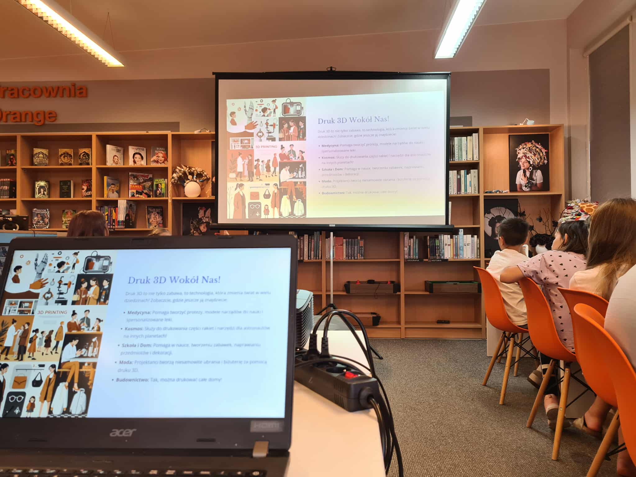 Prezentacja multimedialna o zastosowaniach druku 3D, oglądana przez dzieci w bibliotece.