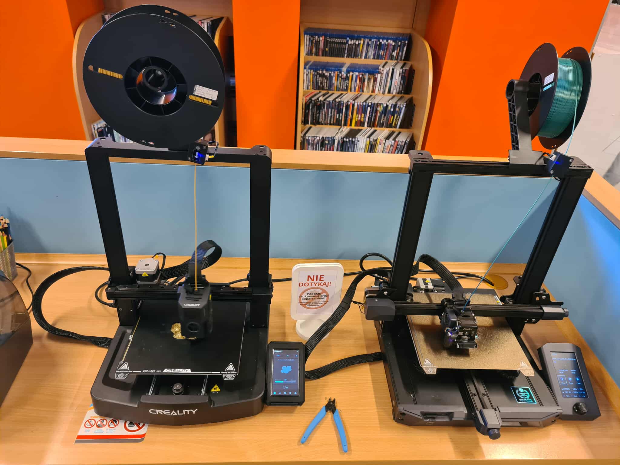 Dwie drukarki 3D Creality pracujące równolegle, obok rolki filamentu.