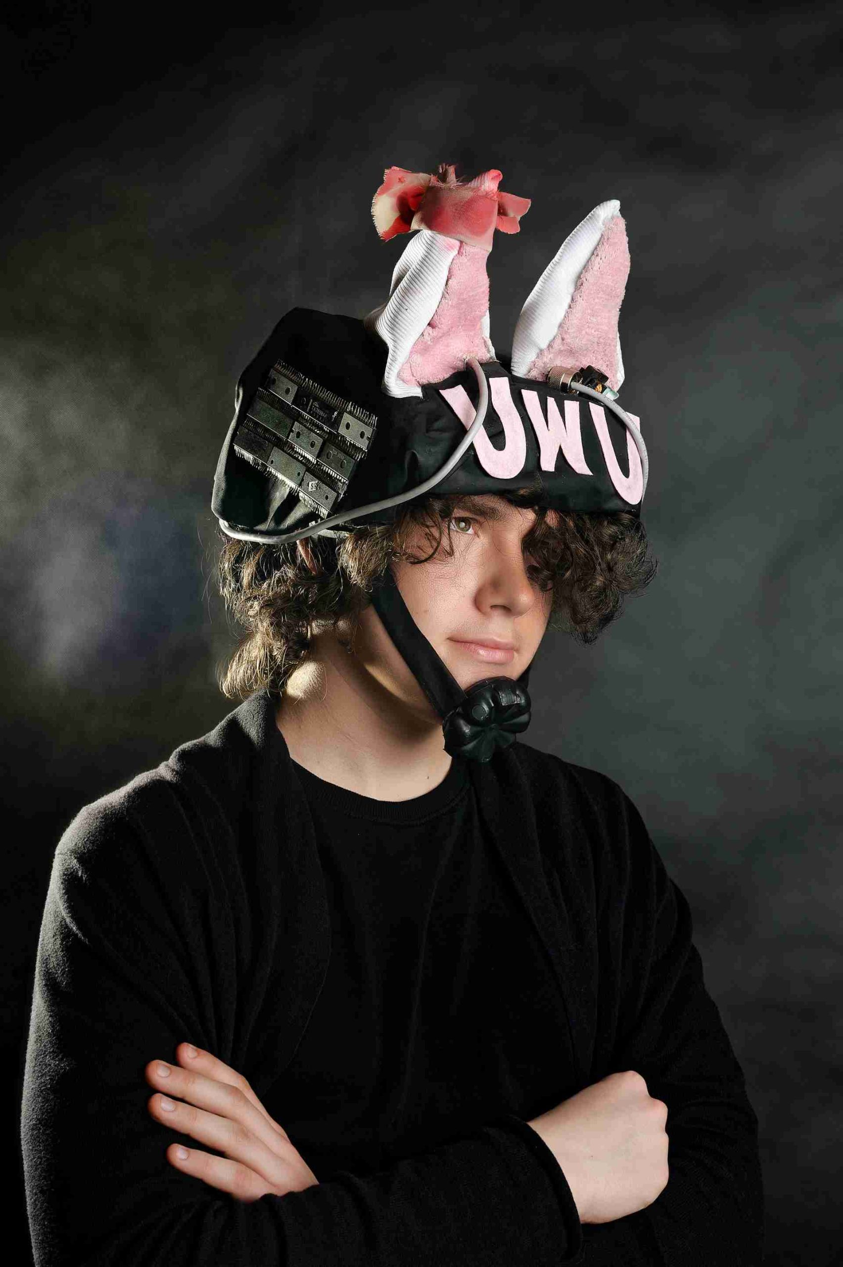 Chłopak w czarnej bluzie z hełmem ozdobionym uszami króliczymi, napisem 