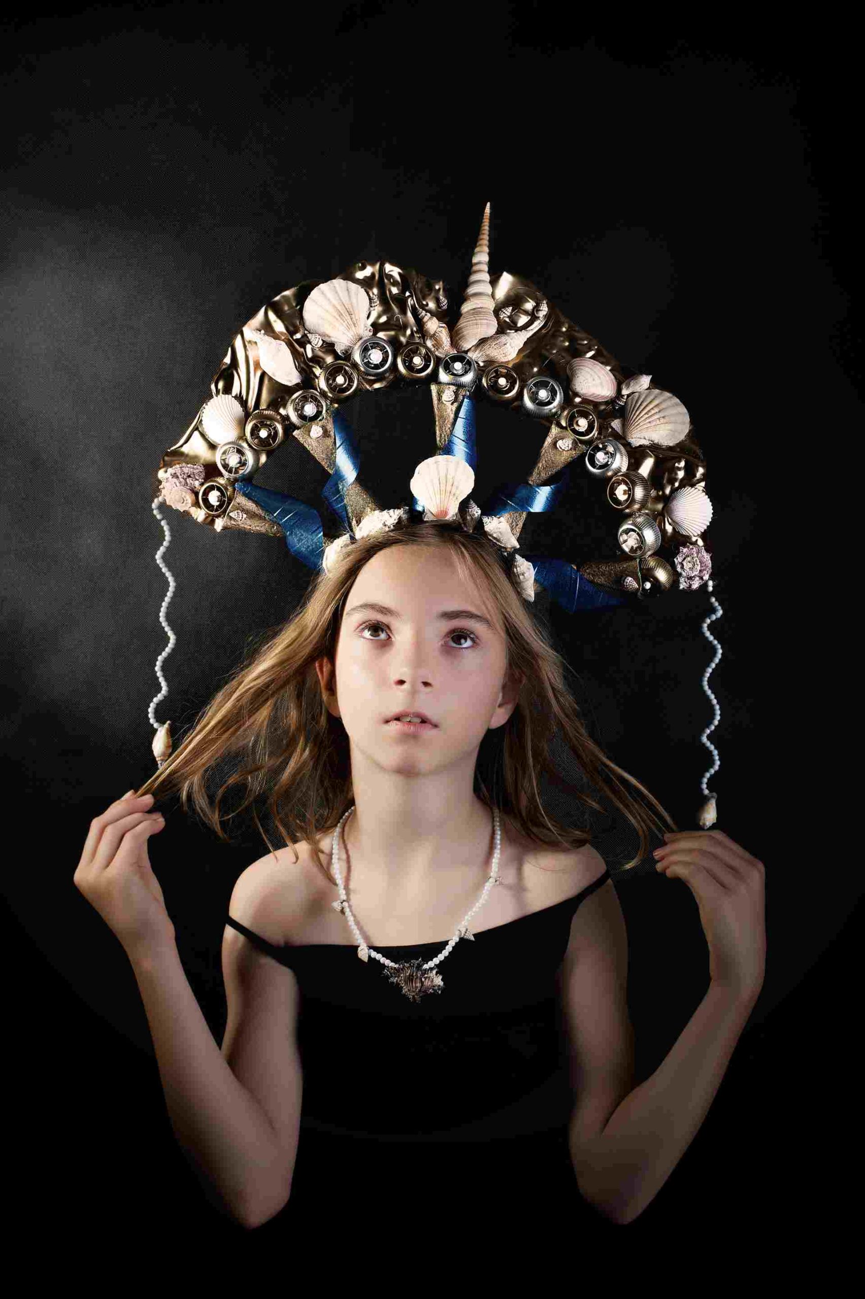 Dziewczynka w morskiej koronie z muszli, pereł i wstążek, z perłową biżuterią.