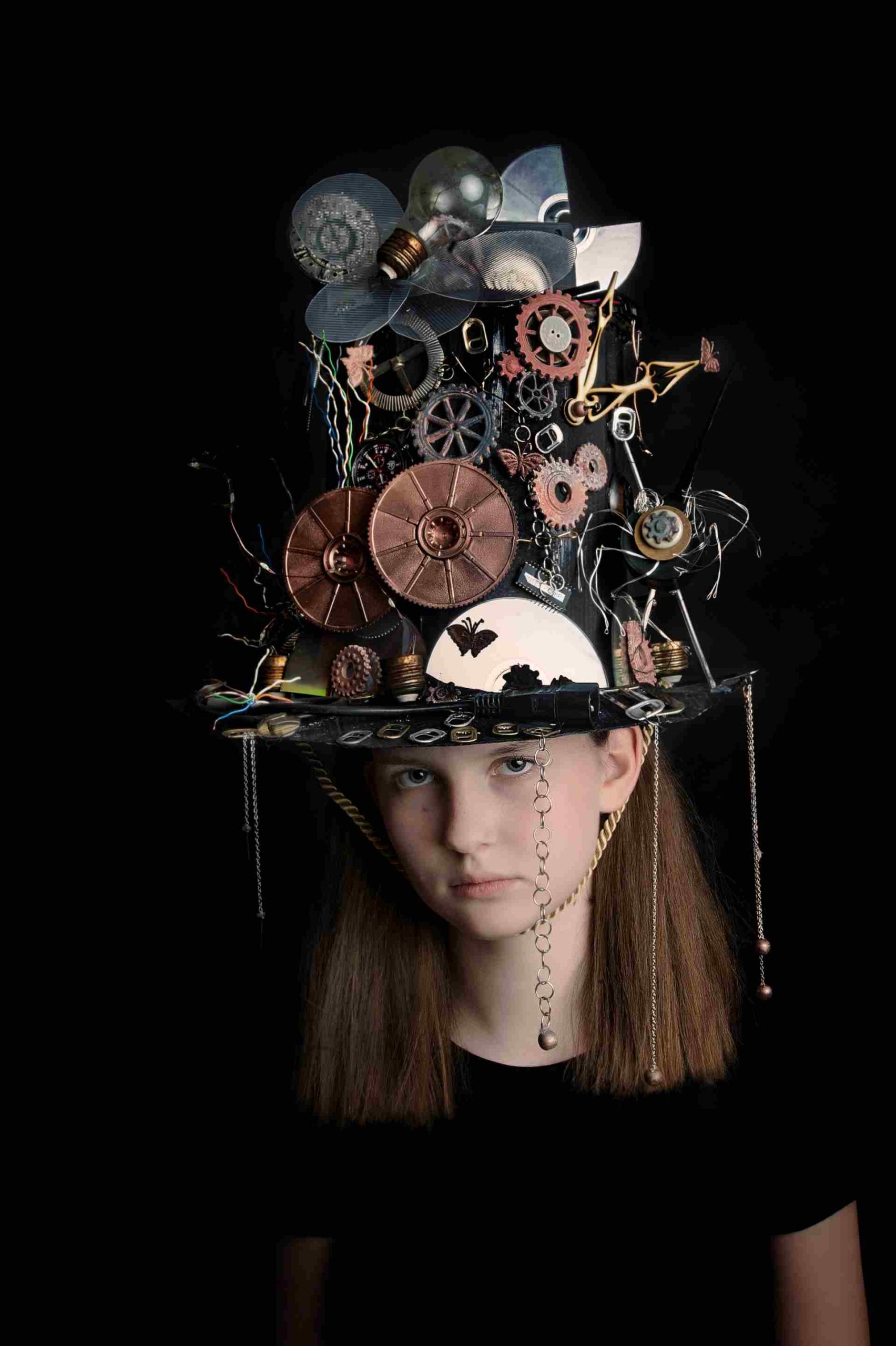 Dziewczyna z wysokim kapeluszem typu steampunk z trybikami, żarówką i kablami, elementy z metalu i elektroniki.